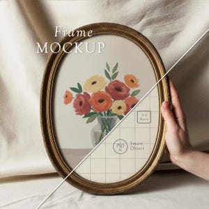 Könnte beinhalten: Ein ovaler goldener Rahmen-Mockup mit dem Text "Frame MOCKUP" oben. Das Kunstwerk im Inneren zeigt einen Strauß aus orangefarbenen, gelben und roten Blumen in einer Glasvase. Der Rahmen wird von einer Hand gehalten.