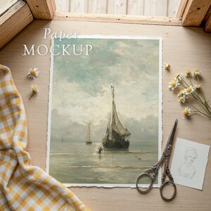 May include: A paper mockup featuring a vintage seascape painting with sailboats. The scene is set on a wooden surface, with scissors, a sketch, and daisies. The text "Paper MOCKUP" is visible.