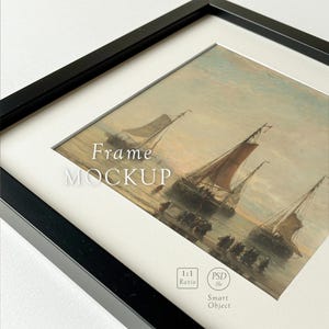 Peut inclure: Cadre noir avec une impression d'art représentant une scène de mer avec des voiliers et des personnages sur le rivage. L'œuvre est encadrée d'un passe-partout blanc, avec les mots "Frame MOCKUP". Le cadre est carré et a un ratio de 1:1.
