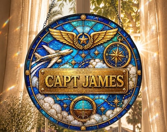 May include: A circular stained glass suncatcher featuring a blue sky background with white clouds, a gold airplane, a gold compass, and a gold winged emblem. A central gold rectangular plaque displays the text CAPT JAMES in bold lettering.