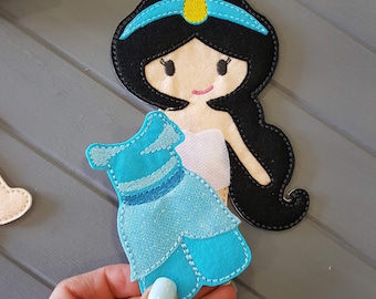 May include: A felt princess doll with black hair, a blue headband, and a turquoise dress. The doll has a white torso and a smiling face. The dress is a light blue color with glitter accents and a dark blue belt.