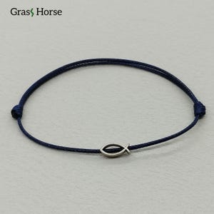 May include: A navy blue cord bracelet with a silver fish charm. The bracelet is adjustable and has a minimalist design. The brand name "Gras Horse" is visible in the top left corner.