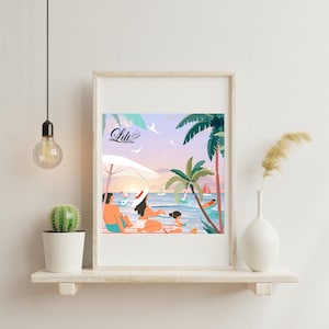 May include: Framed art print featuring a beach scene with people relaxing under a white umbrella. Palm trees, sailboats, and the text "Lili Creations" are visible. The artwork is in a white frame, displayed on a wooden shelf.