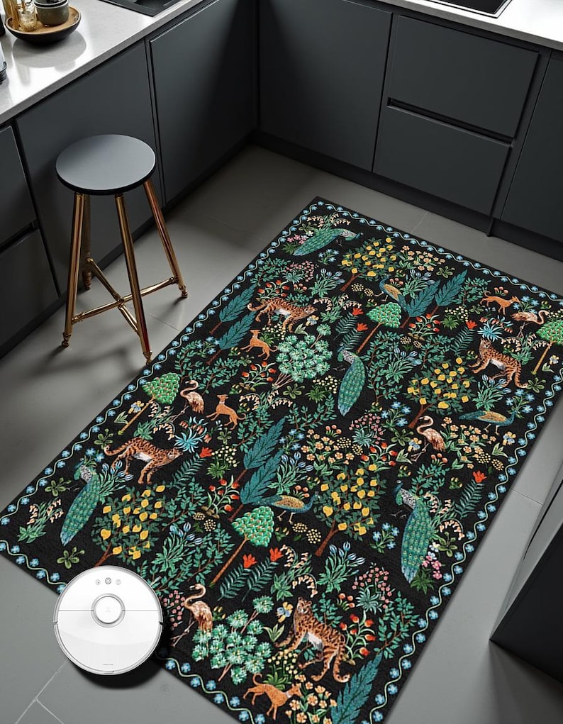 May include: A rectangular black rug with a detailed pattern of animals, trees, and flowers. The design includes leopards, peacocks, and flamingos among lush foliage. The rug is placed on a gray floor in a kitchen setting.