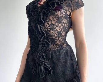 Può includere: Top in pizzo nero con maniche corte e parte anteriore a balze. Il top presenta un delicato motivo floreale in pizzo e un orlo a balze. Un braccialetto d'argento è visibile sul polso sinistro. Stile vintage.