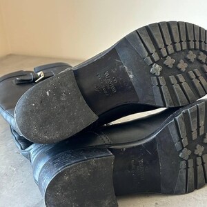Peut inclure: Bottes en cuir noir avec semelle crant&eacute;e. Les bottes ont une boucle et la marque "Valentino" est visible sur la semelle. Les bottes sont de taille 37.