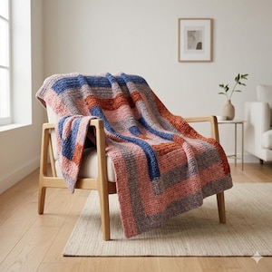 May include: A colorful, knitted throw blanket draped over a wooden armchair. The blanket features a geometric pattern with stripes of blue, orange, pink, and gray. The chair is set on a neutral-colored rug in a well-lit room.