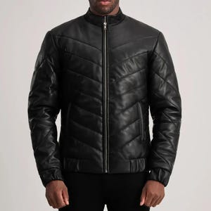 May include: Black leather jacket with a quilted chevron design. The jacket features a stand-up collar, a full-length zipper, and ribbed cuffs and hem. The jacket is a classic style.