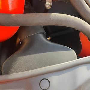 May include: Close-up of a car engine compartment. The image features a black air intake, red silicone hoses, and various other components. The engine bay is partially visible, with a focus on the air intake system.