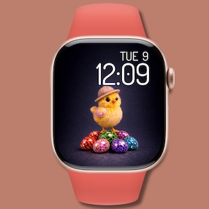 Könnte beinhalten: Eine Smartwatch mit korallenfarbenem Armband und goldfarbenem Gehäuse. Das Zifferblatt zeigt ein gelbes Küken mit Hut, umgeben von bunten, glitzernden Eiern. Die Uhrzeit ist 12:09.