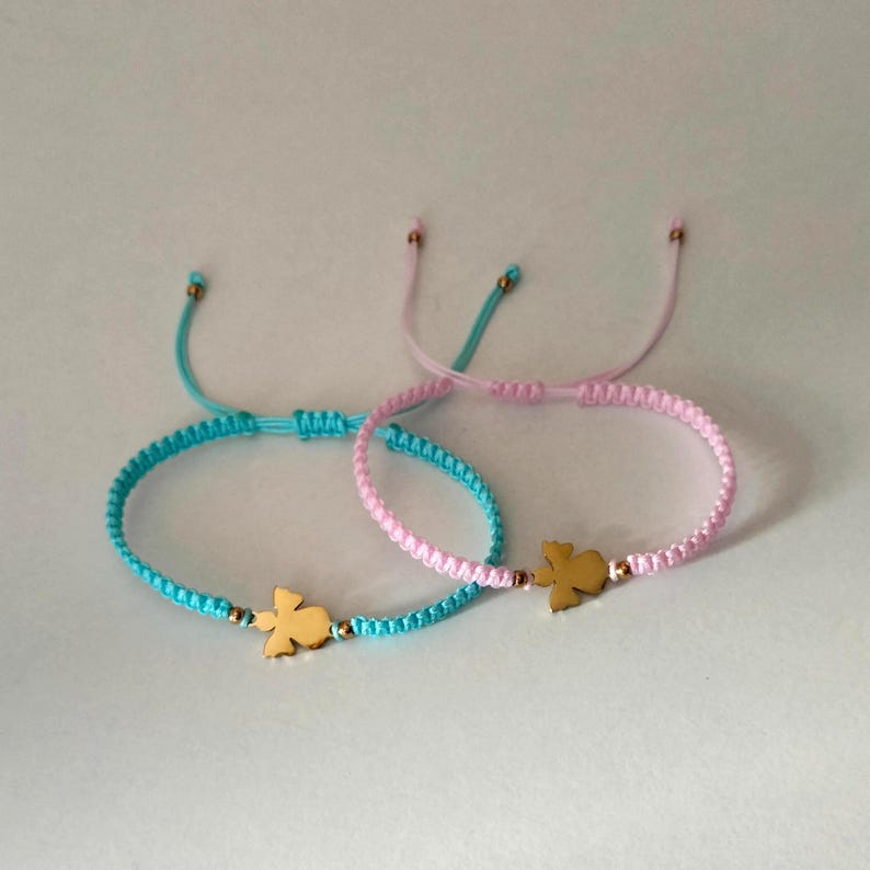 Puede incluir: Dos pulseras de la amistad. Una es azul claro, la otra rosa. Cada pulsera presenta un dije dorado con forma de p&aacute;jaro. Las pulseras son ajustables con un cierre de nudo corredizo. El fondo es de color claro s&oacute;lido.
