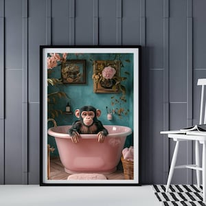 May include: A framed art print featuring a chimpanzee relaxing in a pink bathtub. The bathroom has teal walls, framed floral art, and a small rug. The print is in a black frame and is displayed in a room with a white chair and a black and white striped rug.