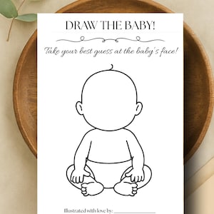 May include: A white baby shower game card with the text "DRAW THE BABY!" and "Take your best guess at the baby's face!" in black. The card features a simple outline of a baby for drawing. The card is on a wooden bowl.