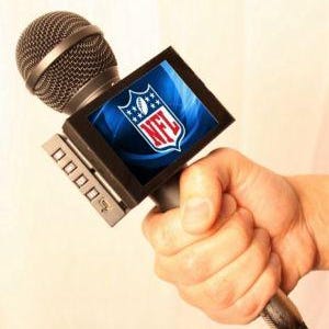 May include: A black microphone with a small screen attached to it. The screen displays the NFL logo. The microphone is being held by a hand.