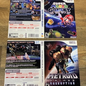 May include: Two Wii game cases are displayed. The top case is for "Super Mario Galaxy," featuring Mario in space. The bottom case is for "Metroid Prime 3: Corruption," with a futuristic character. Both cases have game titles and Nintendo branding.