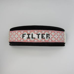 May include: A black beaded dog collar with a pink and white beaded pattern and the word "FILTER" in black lettering.