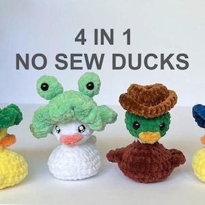 May include: Four plush crocheted duck toys with different hats. The ducks are yellow with black eyes and orange beaks. The hats are green, brown, blue, and white. The text "4 IN 1 NO SEW DUCKS" is above the ducks.