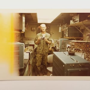 1969 Vietnam War photo of U.S. Navy IC3 inside a Scope Van at Da Nang base, surrounded by vintage electronics and test equipment.
