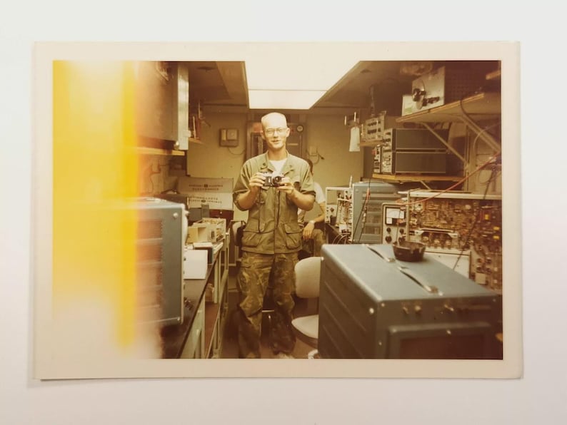 1969 Vietnam War photo of U.S. Navy IC3 inside a Scope Van at Da Nang base, surrounded by vintage electronics and test equipment.