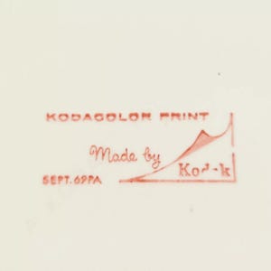 May include: Red text on a white background reads "Kodakolor Print Made by Kod-k Sept. 69PA". A red line with a red mountain shape is drawn under the text.