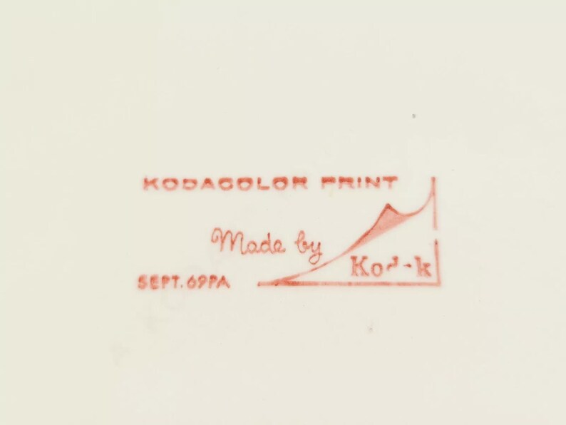 May include: Red text on a white background reads "Kodakolor Print Made by Kod-k Sept. 69PA". A red line with a red mountain shape is drawn under the text.