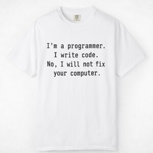 Könnte beinhalten: Ein weißes kurzärmeliges T-Shirt mit schwarzem Text in der Mitte der Brust, der lautet: I'm a programmer. I write code. No, I will not fix your computer. Das T-Shirt hat einen Rundhalsausschnitt und eine Standardpassform mit einem Etikett.