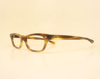 May include: A pair of vintage eyeglasses with a tortoiseshell pattern. The frames are a mix of brown and amber hues, with a rectangular shape and small decorative accents on the temples. The lenses are clear.