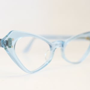 Puede incluir: Un par de gafas de ojo de gato de color azul claro con lentes transparentes.