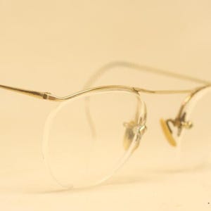 Può includere: Un paio di occhiali in metallo dorato con lenti trasparenti. Gli occhiali hanno un design senza montatura e sono in buone condizioni.