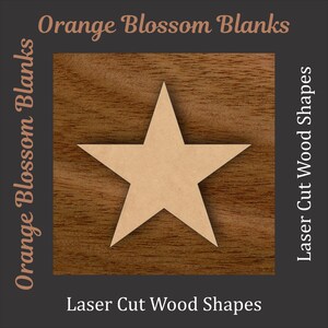 May include: A laser-cut wooden star shape, centered on a dark brown square with a wood grain texture. The text "Orange Blossom Blanks" and "Laser Cut Wood Shapes" are displayed in a serif font.