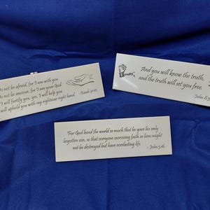 May include: Three rectangular white plaques with inspirational quotes in black text. One plaque reads "Do not be afraid..." with a hand graphic. Another says "And you will know the truth..." with a handcuff graphic. The third says "For God loved the world..."