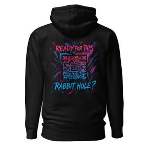 Op de afbeelding: Zwarte hoodie met de tekst "READY FOR THIS RABBIT HOLE?" in blauw en roze op de rug, samen met een QR-code afbeelding. Het ontwerp heeft een spatteffect.