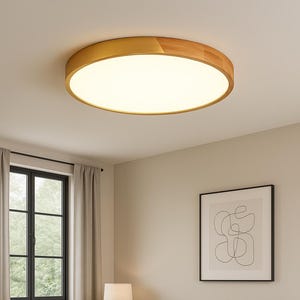 Könnte beinhalten: Eine runde Deckenleuchte mit Holzrahmen und hellem, weißem Lichtpaneel. Die Leuchte ist der Mittelpunkt eines Wohnzimmers mit neutralen Tönen, einem Sofa und einem gerahmten abstrakten Kunstwerk.