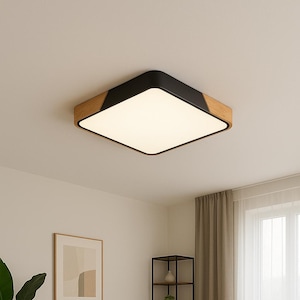 May include: Square flush-mount ceiling light fixture with a black frame, wood accents, and a bright white light panel. The light is installed in a modern living room with a sofa, coffee table, and artwork.