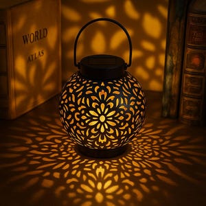 Solar-powered hanging lantern with floral cutouts. Adds warm, ambient light to your garden, patio, or yard. Eco-friendly & elegant design.