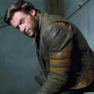 May include: A brown leather jacket with tan stripes on the sleeves. The jacket is worn with blue jeans. The person is holding three metal claws.