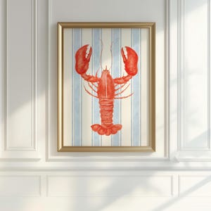 May include: A framed print featuring a vibrant red lobster illustration. The lobster is centered against a backdrop of vertical blue and white stripes. The artwork is encased in a gold-colored frame, adding a touch of elegance.