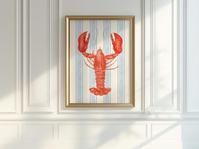 May include: A framed print featuring a vibrant red lobster illustration. The lobster is centered against a backdrop of vertical blue and white stripes. The artwork is encased in a gold-colored frame, adding a touch of elegance.