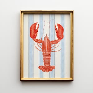 Peut inclure: Une impression encadrée à l'aquarelle représentant un homard rouge vif sur un fond de rayures verticales bleues et blanches. Le homard est détaillé avec des pinces et des antennes visibles, le tout dans un cadre doré. L'œuvre évoque un thème nautique ou côtier.