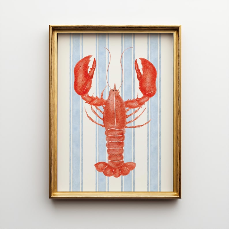 May include: A framed watercolor print featuring a vibrant red lobster against a backdrop of vertical blue and white stripes. The lobster is detailed with visible claws and antennae, set within a gold-colored frame. The artwork evokes a nautical or coastal theme.
