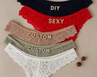 May include: An assortment of lace underwear in navy, red, tan, sage green, and white. The navy pair has the word "DIY" in rhinestones, the red pair has "SEXY", and two pairs have "CUSTOM". The underwear has a delicate floral lace pattern.