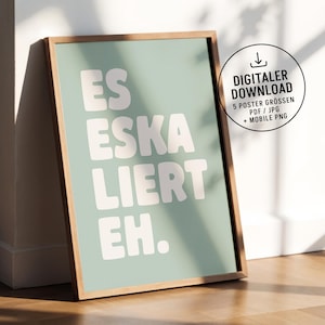 Könnte beinhalten: Gerahmtes Poster mit den Worten "ES ESKA LIERT EH" in weißen, fetten Buchstaben auf hellgrünem Hintergrund. Der Rahmen besteht aus hellbraunem Holz. Eine kreisförmige Grafik mit Text befindet sich in der oberen rechten Ecke.