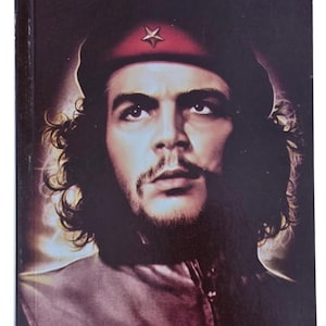 May include: A book cover featuring a portrait of Che Guevara wearing a dark beret with a red star. The background is black with a glowing light effect around the hair. The text in Punjabi script reads 'Che Guevara' at the top and 'Dharam Singh Goraya' at the bottom.