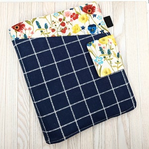 May include: A blue and white checked fabric pouch with a floral print pocket. The pouch has a white zipper pull and a small floral print pocket on the front.