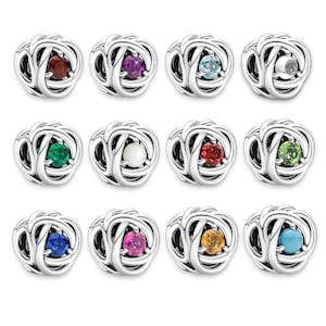 May include: A collection of silver-toned charms, each featuring a colorful gemstone center. The gemstones vary in color, including red, purple, blue, green, and yellow. The charms have a woven, knot-like design.