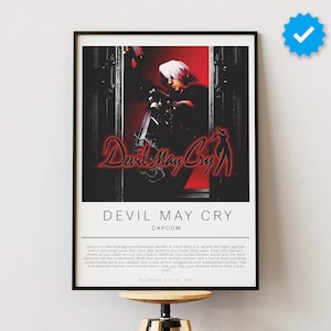 May include: Framed poster featuring the "Devil May Cry" video game. The artwork showcases a character with white hair and a weapon, set against a red and black background. The title is in red, stylized text. The poster is displayed on a white wall.