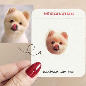 May include: A custom pin featuring a small, light-colored dog with its tongue out, displayed on a white card with the text MIXICHARMS at the top and Handmade with love at the bottom, alongside a reference photo of the same dog.