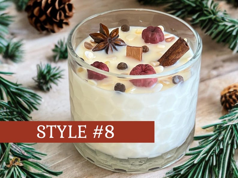 May include: A clear glass candle holder with a textured honeycomb pattern filled with white wax. The top is decorated with a star anise, a cinnamon stick, dark peppercorns, and small red dried fruits. A wooden wick is centered. Text reads STYLE #8.