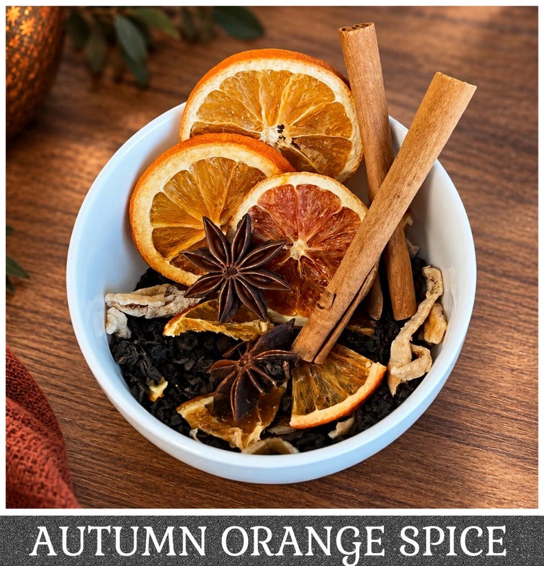 May include: A white bowl filled with loose black tea leaves, dried orange slices, two brown cinnamon sticks, and two dark brown star anise pods. The text AUTUMN ORANGE SPICE is printed in white capital letters at the bottom of the image.