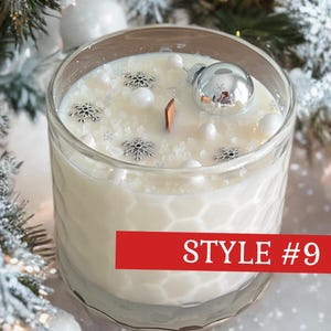May include: A white candle in a clear glass jar with a honeycomb texture. The wax surface is decorated with silver snowflake charms, white beads, and a small silver ornament. A wooden wick is centered. A red banner displays the text STYLE #9.